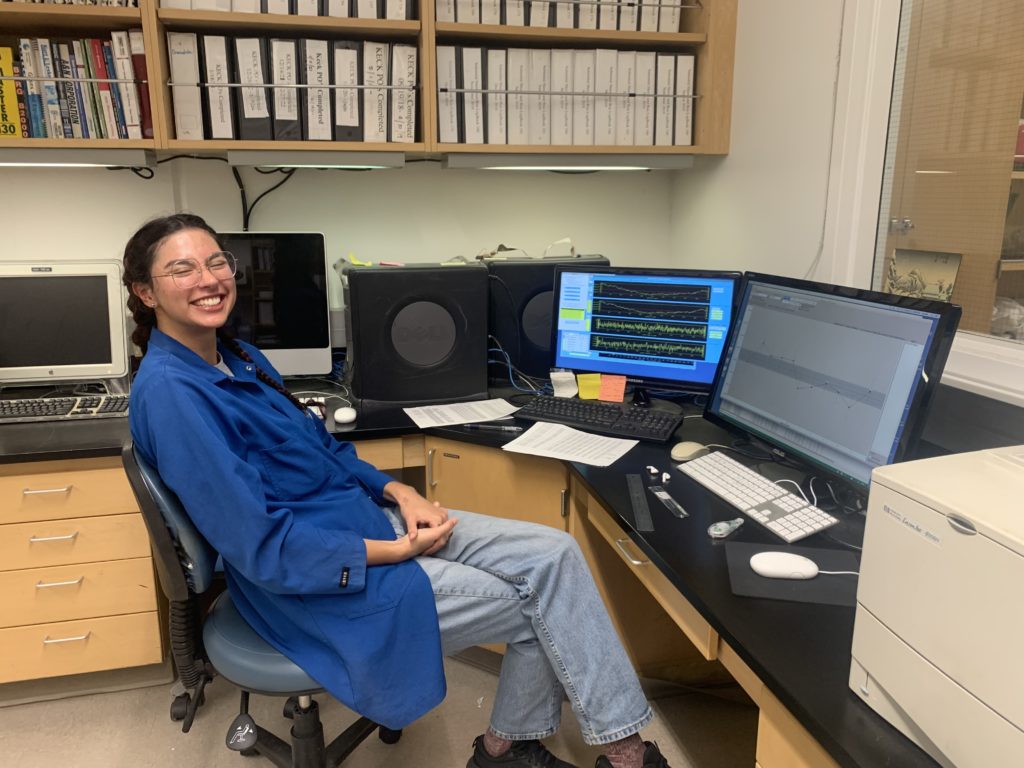 Giselle Jimenez sitting facing computer screens connected to spectrometer