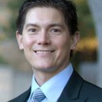 Thomas Jaramillo smiling wearing dark suit with blue shirt and tie